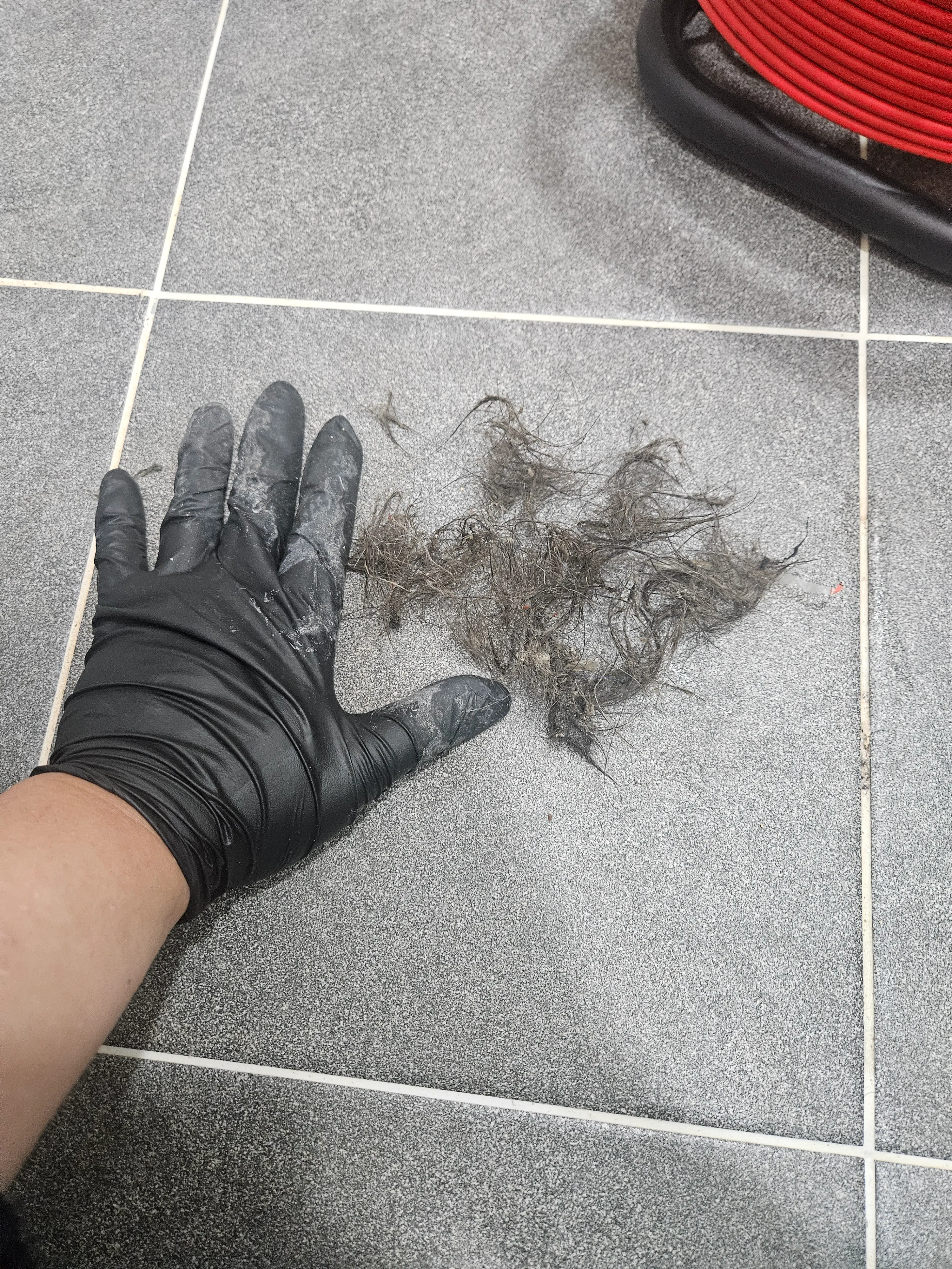 하수구 막힘 스케일링 후 바닥 타일에 수거된 대량의 머리카락 뭉치와 기름 찌꺼기 잔해