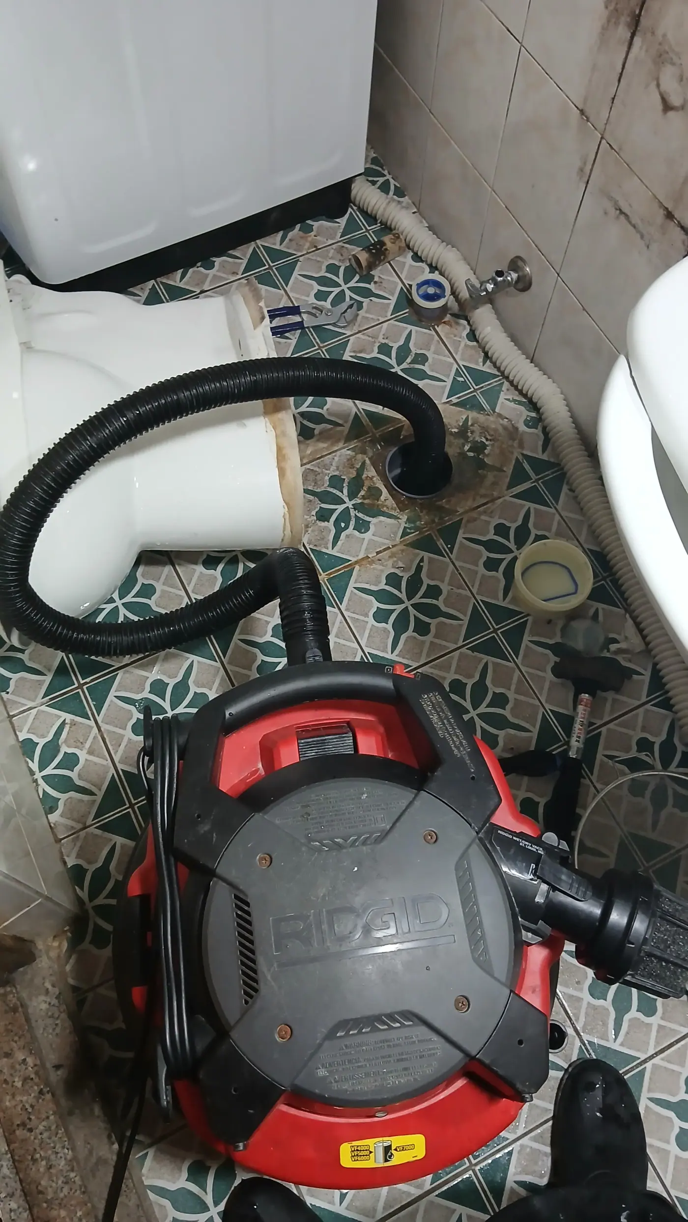 화장실 바닥 하수구 옆에 세팅된 붉은색 RIDGID 강력 석션기 모습