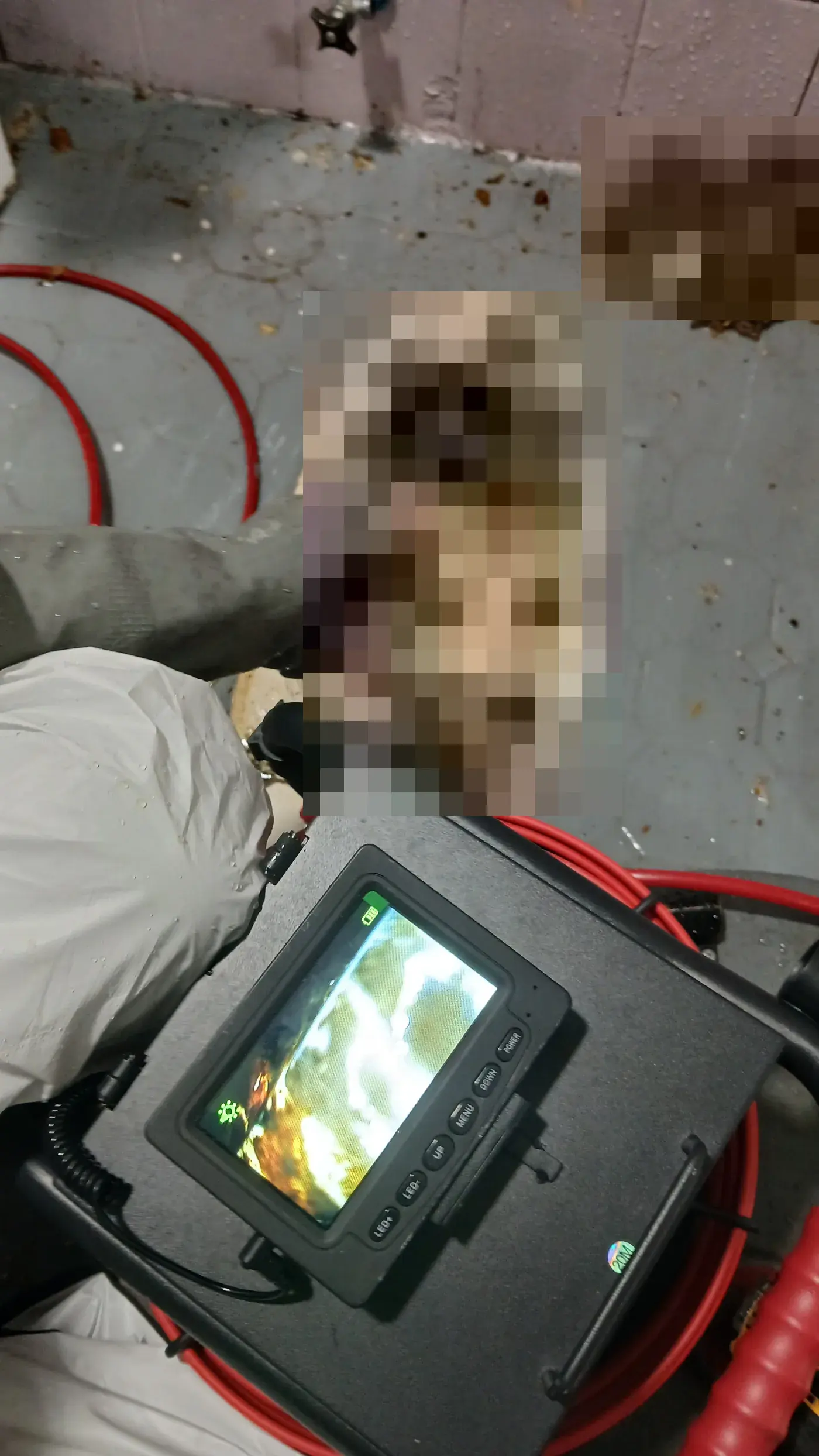 변기를 탈거한 오수관에 내시경 카메라를 넣어 모니터로 내부를 확인하는 모습