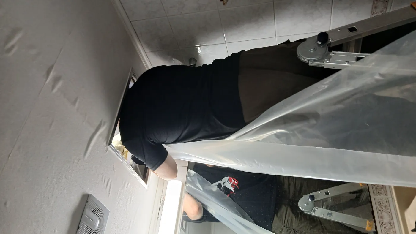 사다리 위에서 화장실 천장 점검구 안쪽 마무리 작업을 진행하는 작업자